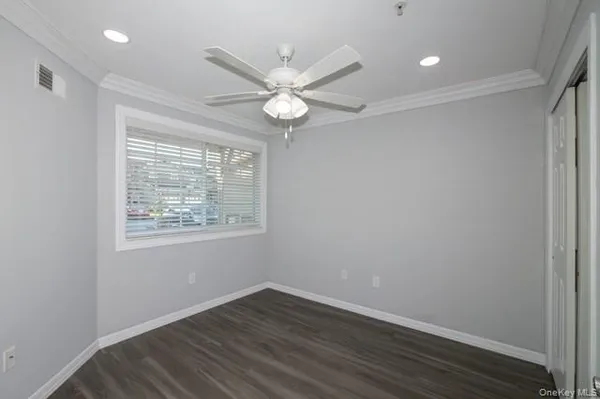 an empty room with wooden floor fan and windows