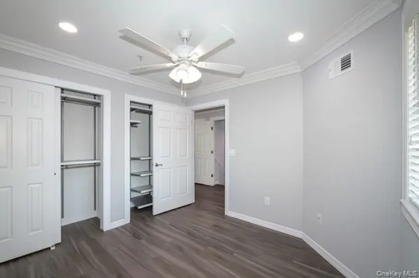 an empty room with wooden floor closet and windows