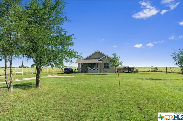 a view of a house with a big yard and a large tree