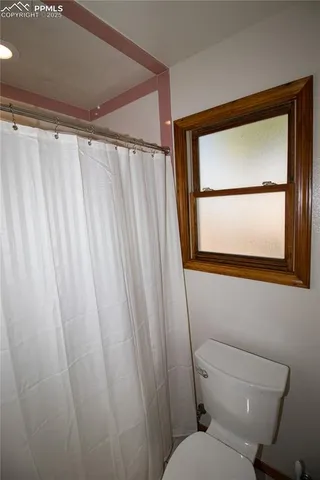 a bathroom with a toilet and a shower curtain