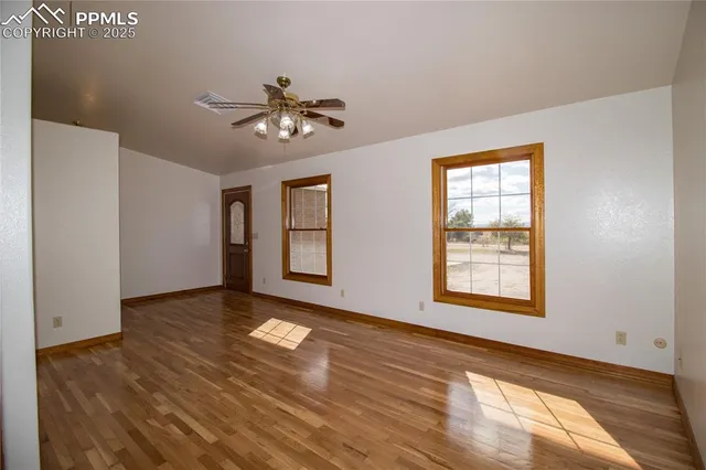 a view of empty room with wooden floor and fan