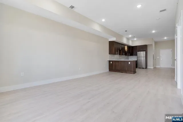 an empty room with kitchen and windows