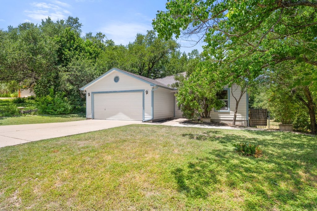 5208 Sioux Lane Austin, TX 78734 - Photo 4 of 35 A charming single-story residence with an integrated garage is framed by mature trees and lush green landscaping.