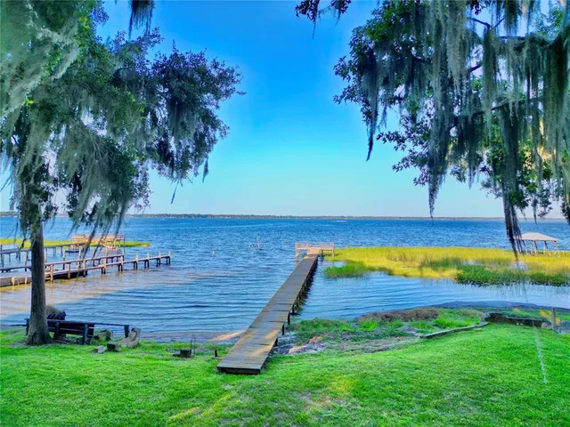 a view of swimming pool with lawn chairs and a big yard