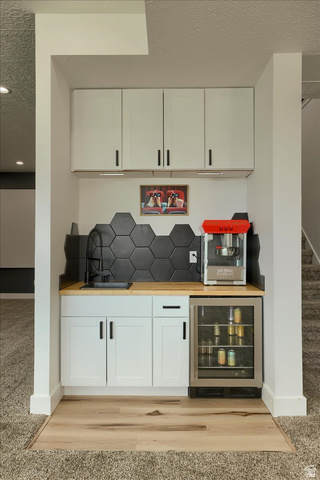 828 South Deer Road Tooele, UT 84074 - Photo 13 of 51 Built-in wet bar featuring white shaker-style cabinetry, a light wood-finish countertop, and a black hexagonal tile backsplash