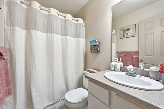 5196 Rodeo Circle Oakley, UT 84055 - Photo 26 of 57 Additional Main floor Bathroom featuring an integrated sink vanity with a light-toned countertop, a large wall-mounted mirror, and a toilet