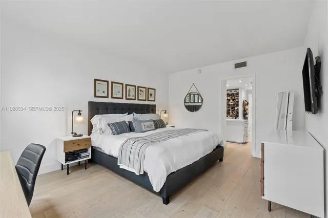 a bedroom with a bed a couch and a flat tv screen on the dresser