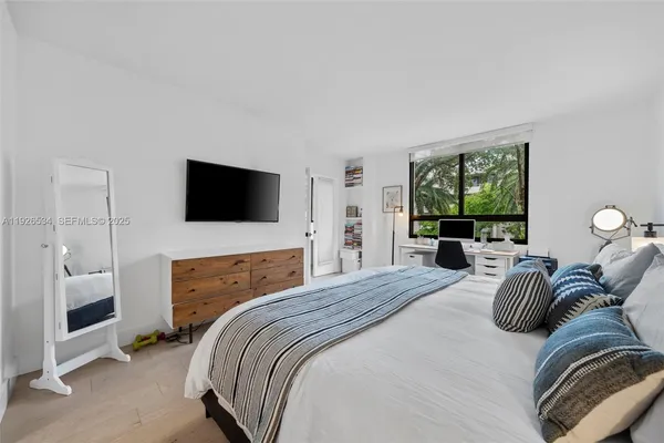 a bedroom with a bed a window and a flat screen television