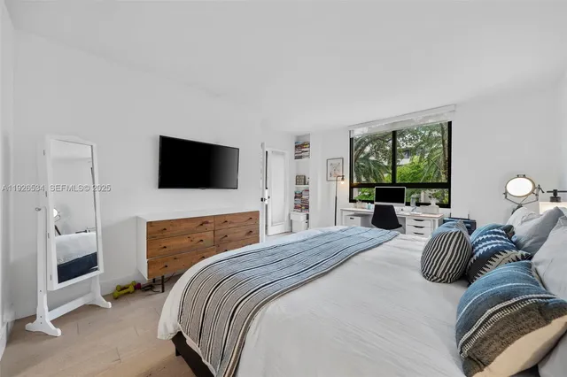 a bedroom with a bed a window and a flat screen television