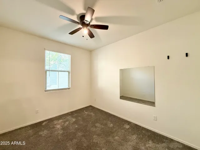 an empty room with a window and a ceiling fan