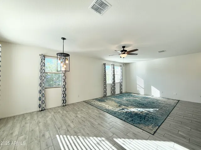 a view of an empty room with window and chandelier fan
