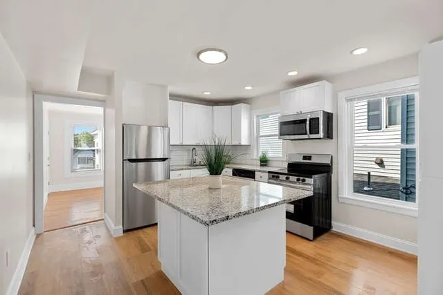 a kitchen with stainless steel appliances granite countertop a sink stove microwave and refrigerator