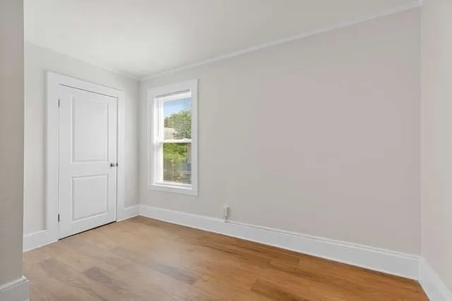 a view of an empty room with wooden floor and a window