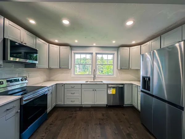 a kitchen with stainless steel appliances granite countertop refrigerator sink and microwave