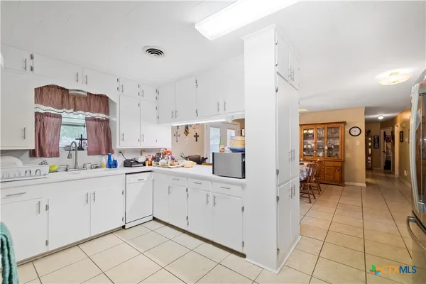 a kitchen with white cabinets and sink