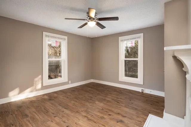an empty room with wooden floor and windows