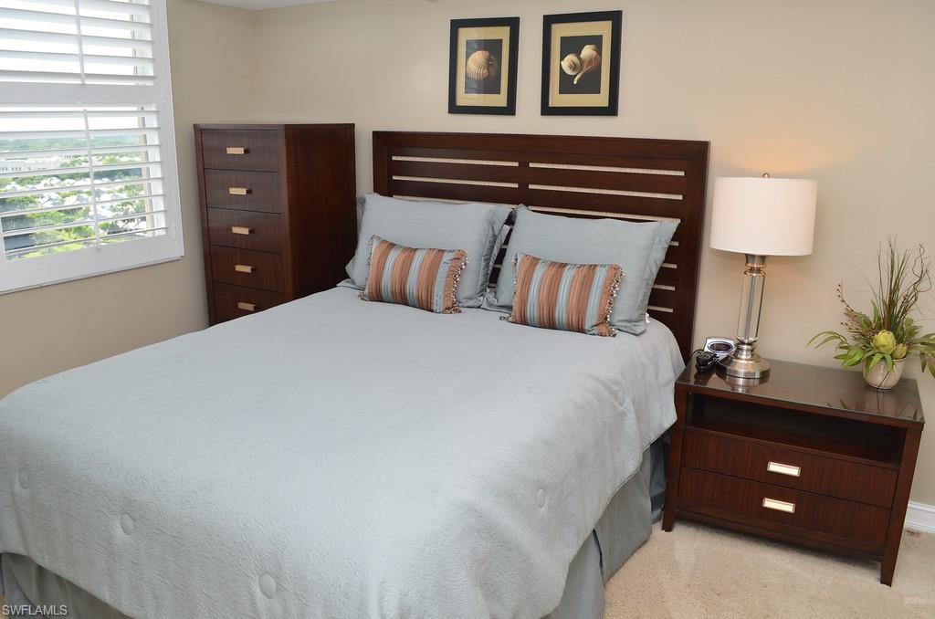 5550 Heron Point Drive, Unit 1804 Naples, FL 34108 - Photo 12 of 17 a bedroom with a bed and a lamp on dresser