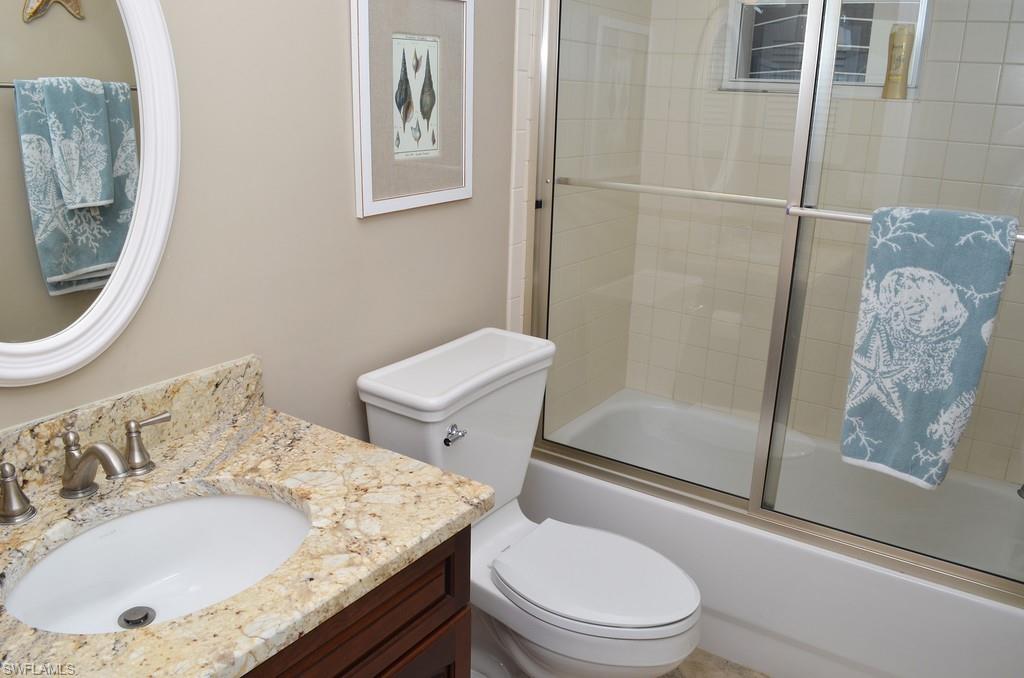 5550 Heron Point Drive, Unit 1804 Naples, FL 34108 - Photo 15 of 17 a bathroom with a granite countertop sink a toilet and shower