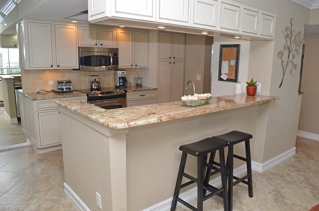 5550 Heron Point Drive, Unit 1804 Naples, FL 34108 - Photo 10 of 17 a kitchen with stainless steel appliances granite countertop a sink a stove a microwave and cabinets