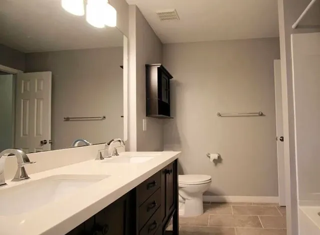 a bathroom with a granite countertop sink toilet and shower