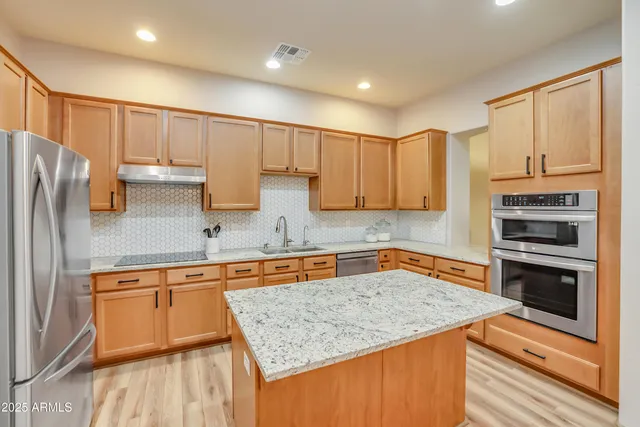 a kitchen with stainless steel appliances granite countertop a sink stove and refrigerator