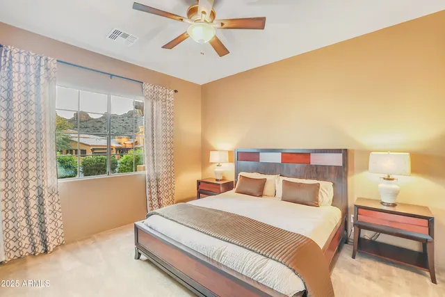 a bedroom with a large bed and a chandelier fan