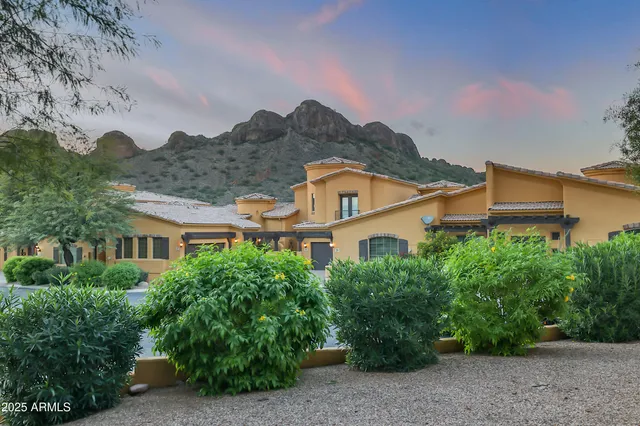 a view of a white house next to a yard with large trees