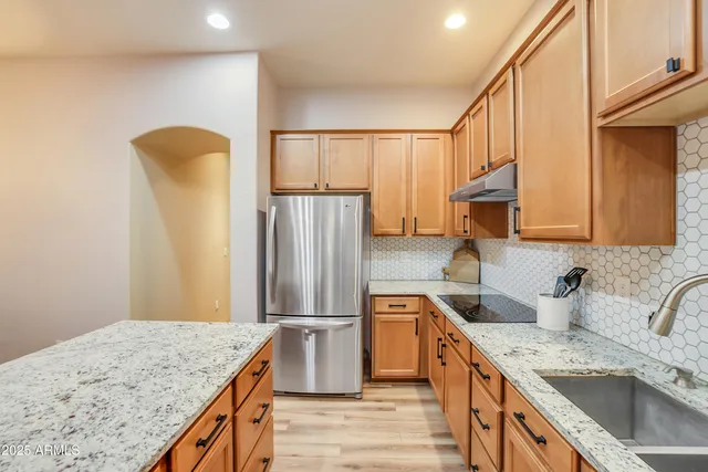 a kitchen with stainless steel appliances granite countertop a sink refrigerator and cabinets