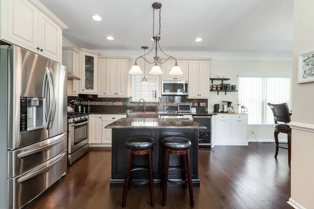 a kitchen with granite countertop a center island stainless steel appliances cabinets and a window
