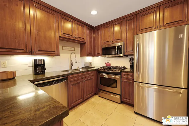 a kitchen with stainless steel appliances granite countertop a refrigerator stove top oven a sink and dishwasher