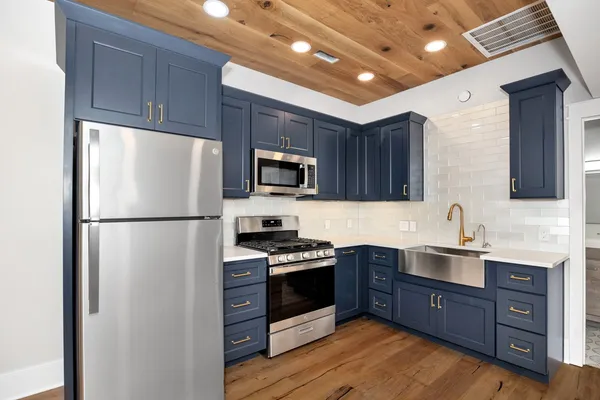 a kitchen with stainless steel appliances a refrigerator a sink a stove a microwave and wooden floors