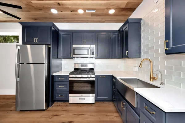 a kitchen with granite countertop a refrigerator stove and microwave