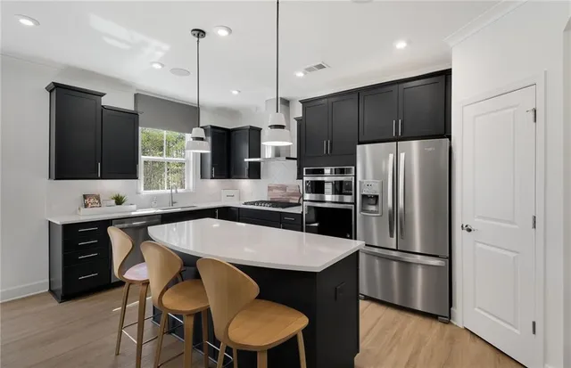 a kitchen with stainless steel appliances a refrigerator a sink a stove a dining table and chairs