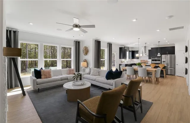 a living room with lots of furniture wooden floor and a large window