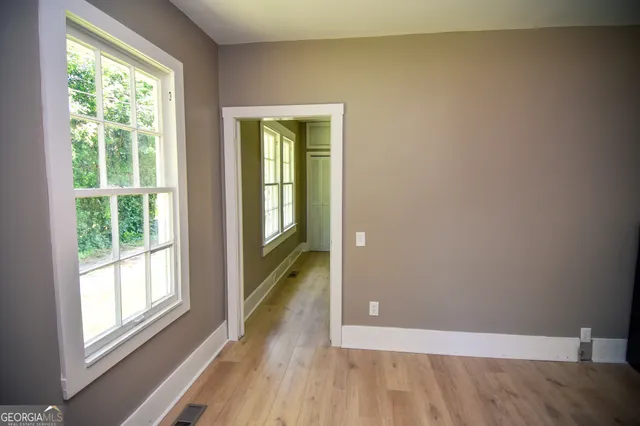a view of an empty room with wooden floor and a window