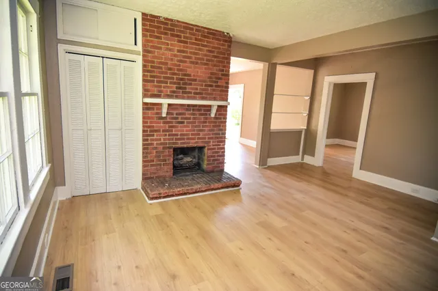an empty room with wooden floor and fireplace