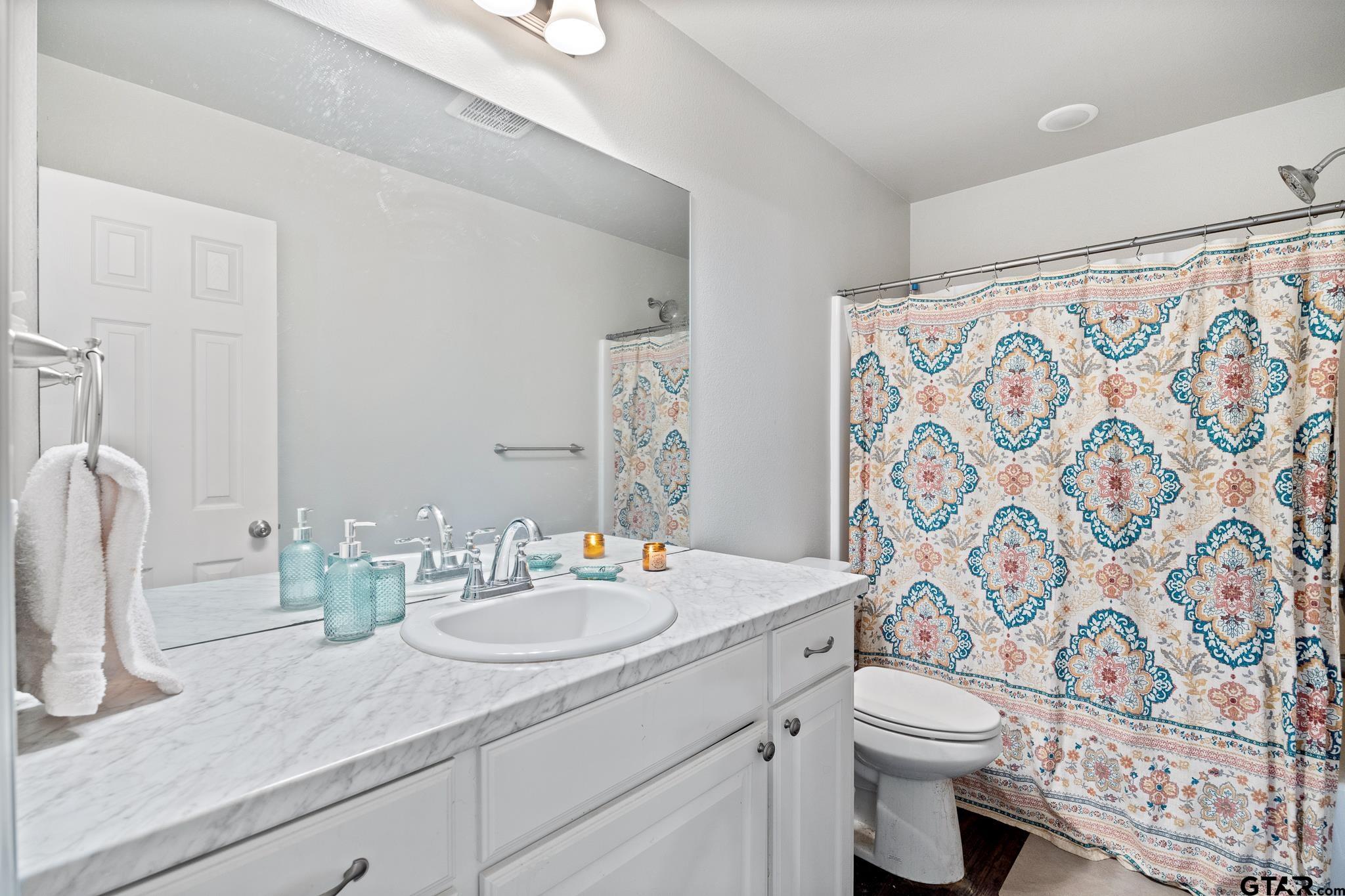 421 Alexander Street Kilgore, TX 75662 - Photo 17 of 24 a bathroom with a granite countertop sink a toilet and a mirror