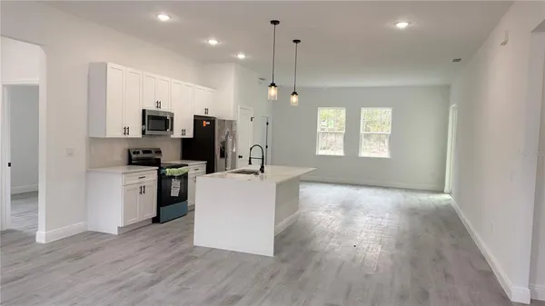 a large kitchen with a wooden floor and stainless steel appliances
