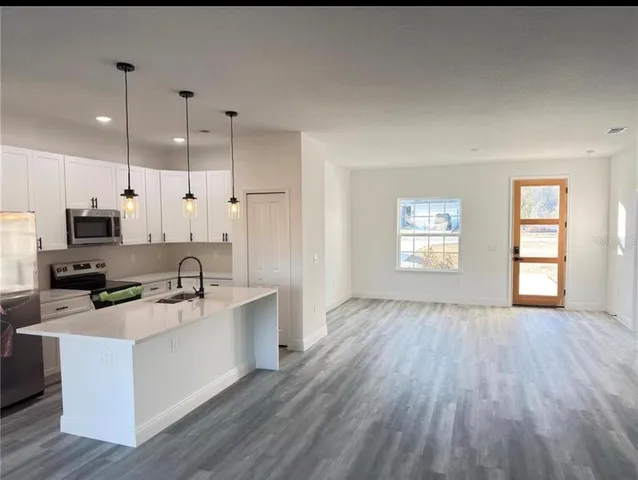 a large kitchen with cabinets wooden floor and stainless steel appliances