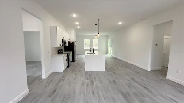 a view of a big room with wooden floor and a kitchen