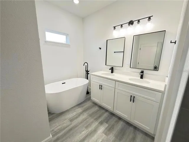 a spacious bathroom with a double vanity sink mirror and bathtub