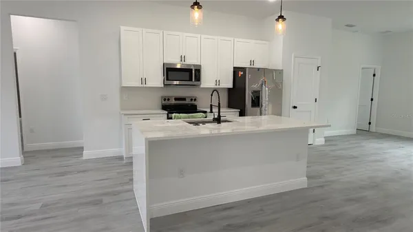 a kitchen with stainless steel appliances a refrigerator a sink a stove a microwave and wooden floors