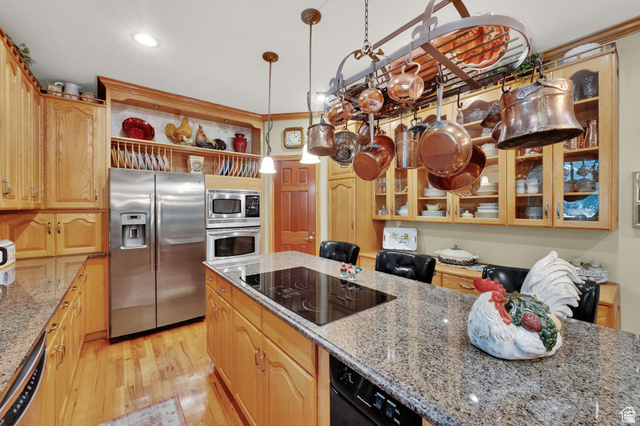 7740 Keswick Road Sandy, UT 84093 - Photo 18 of 74 Kitchen featuring granite countertops, wood-finish flooring, stainless steel appliances, wood cabinetry, and a central island with an integrated cooktop
