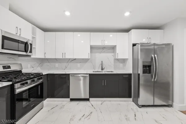 a kitchen with granite countertop a refrigerator and a stove top oven