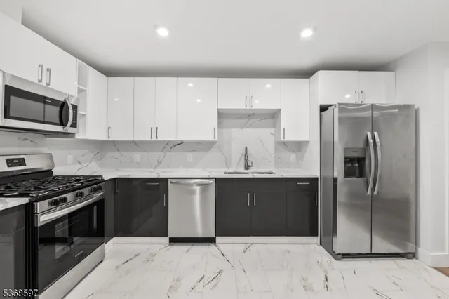 a kitchen with granite countertop a refrigerator and a stove top oven