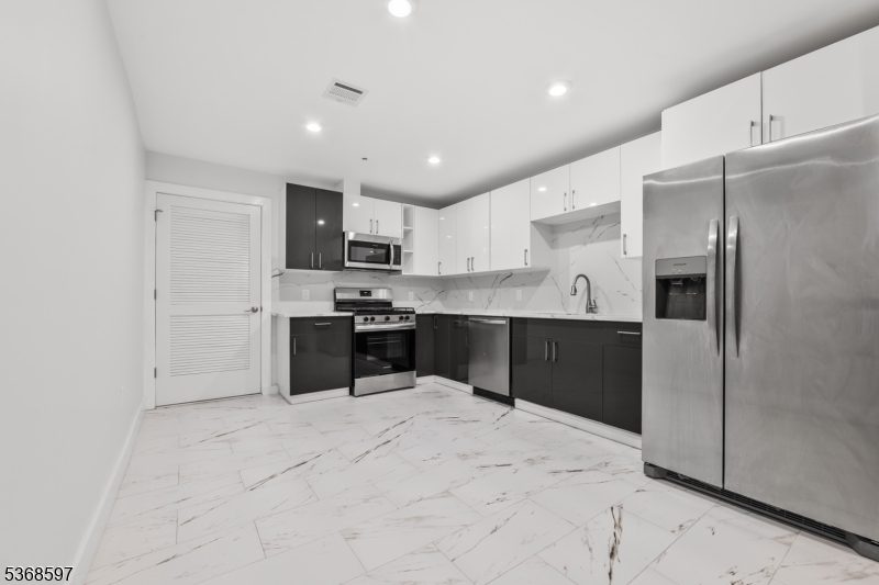 180 Carroll Street Paterson, NJ 07501 - Photo 14 of 31 a kitchen with stainless steel appliances kitchen island granite countertop a refrigerator sink and cabinets