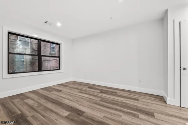 a view of an empty room with a window and wooden floor