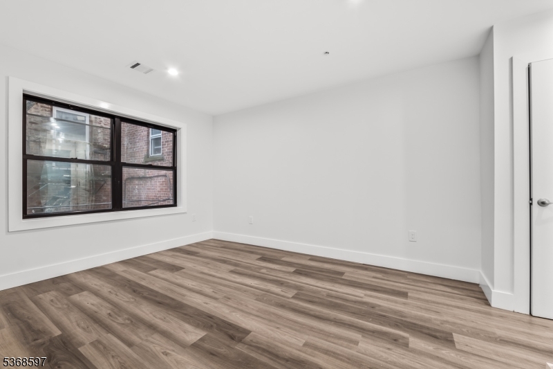 180 Carroll Street Paterson, NJ 07501 - Photo 20 of 31 a view of an empty room with a window and wooden floor