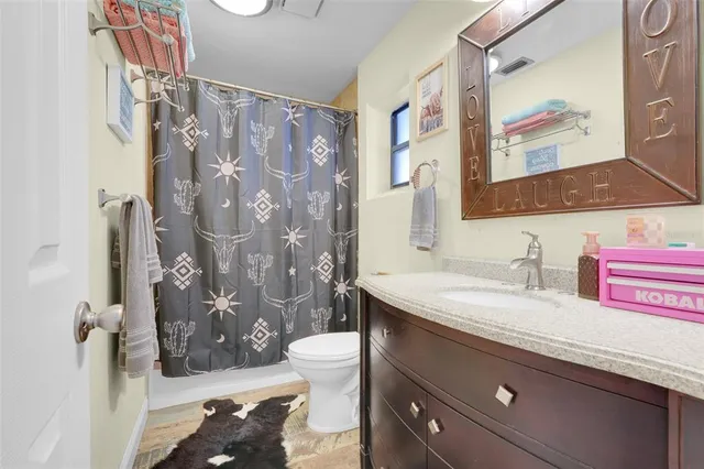 a bathroom with a granite countertop sink a toilet and a shower curtain