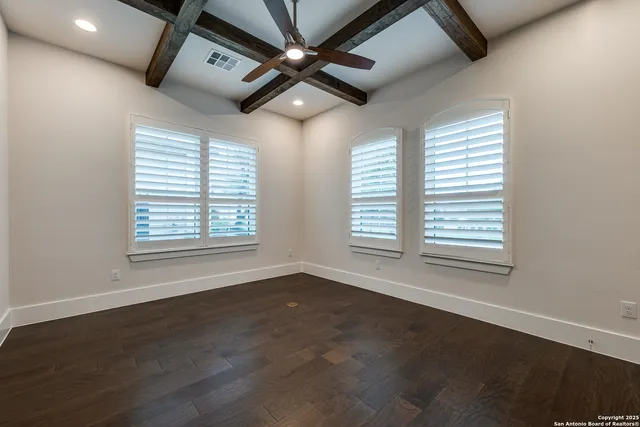 a view of an empty room with a window and wooden floor